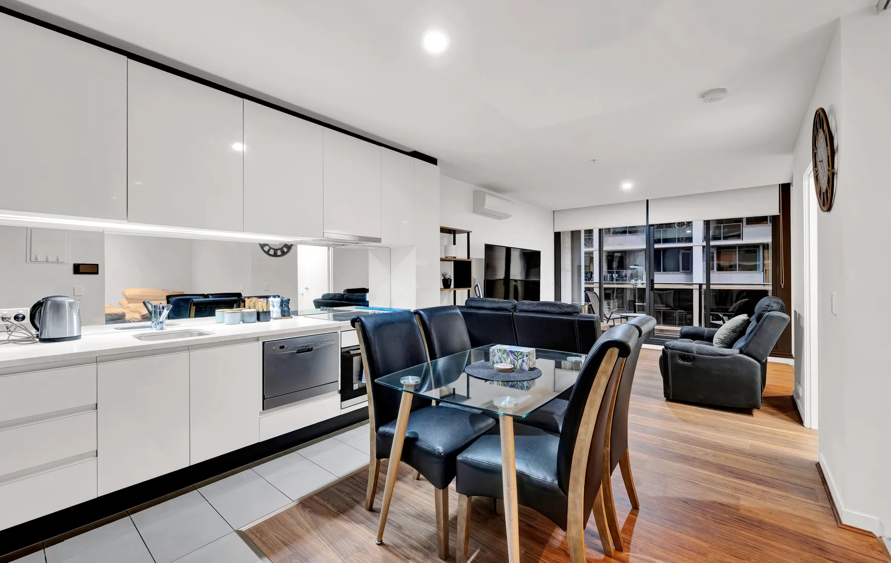 An open-plan kitchen and dining area with a dark seating area beside the windows.