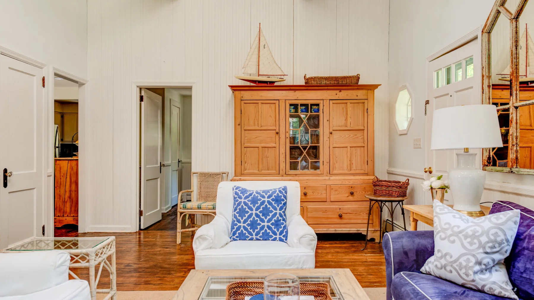 A bright living room with cushioned seating and a large wooden cabinet.