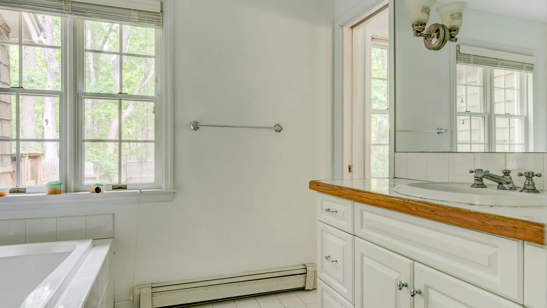 A bright bathroom with a bathtub, vanity, and large windows.