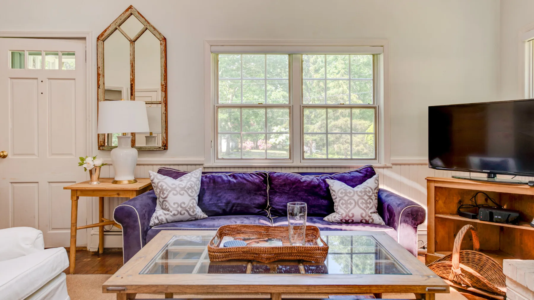 A living room with purple seating arranged around a glass-top coffee table.
