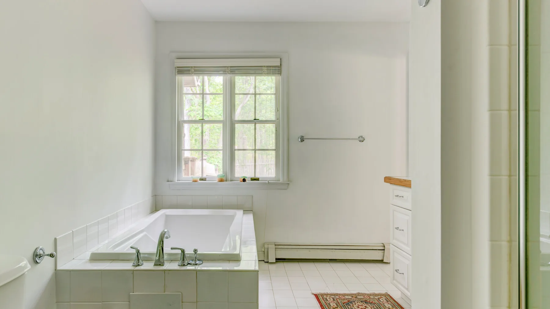A bright bathroom with a bathtub beneath a window.