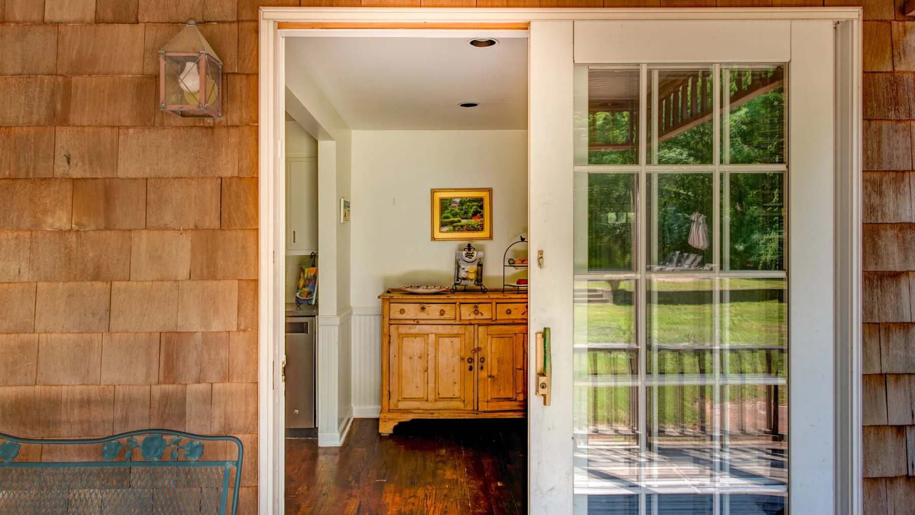 An open doorway reveals a bright interior with a wooden cabinet and glass door.