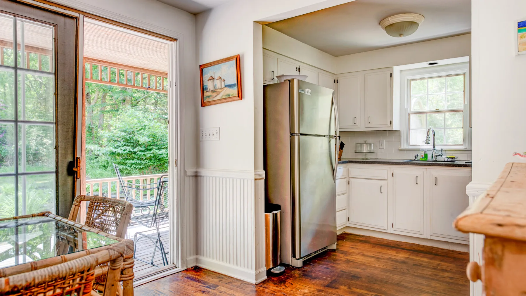 A bright kitchen with white cabinets and a stainless steel refrigerator.