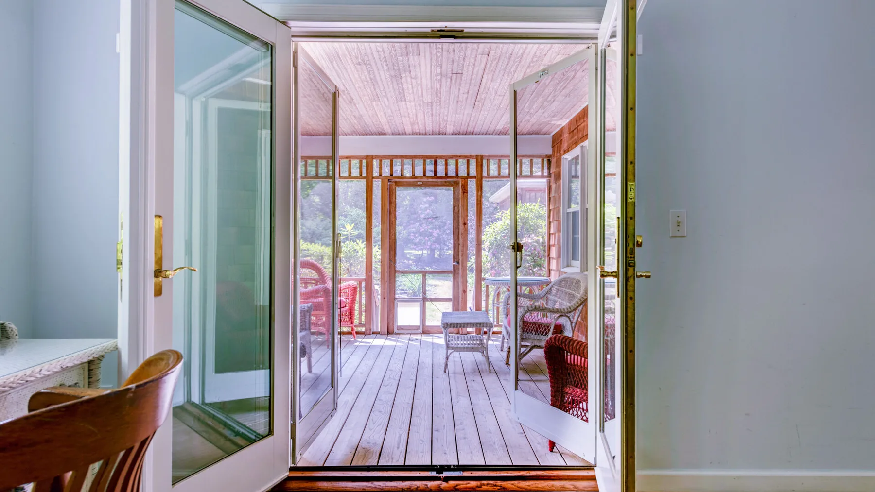 An open doorway leads onto a screened porch with seating.