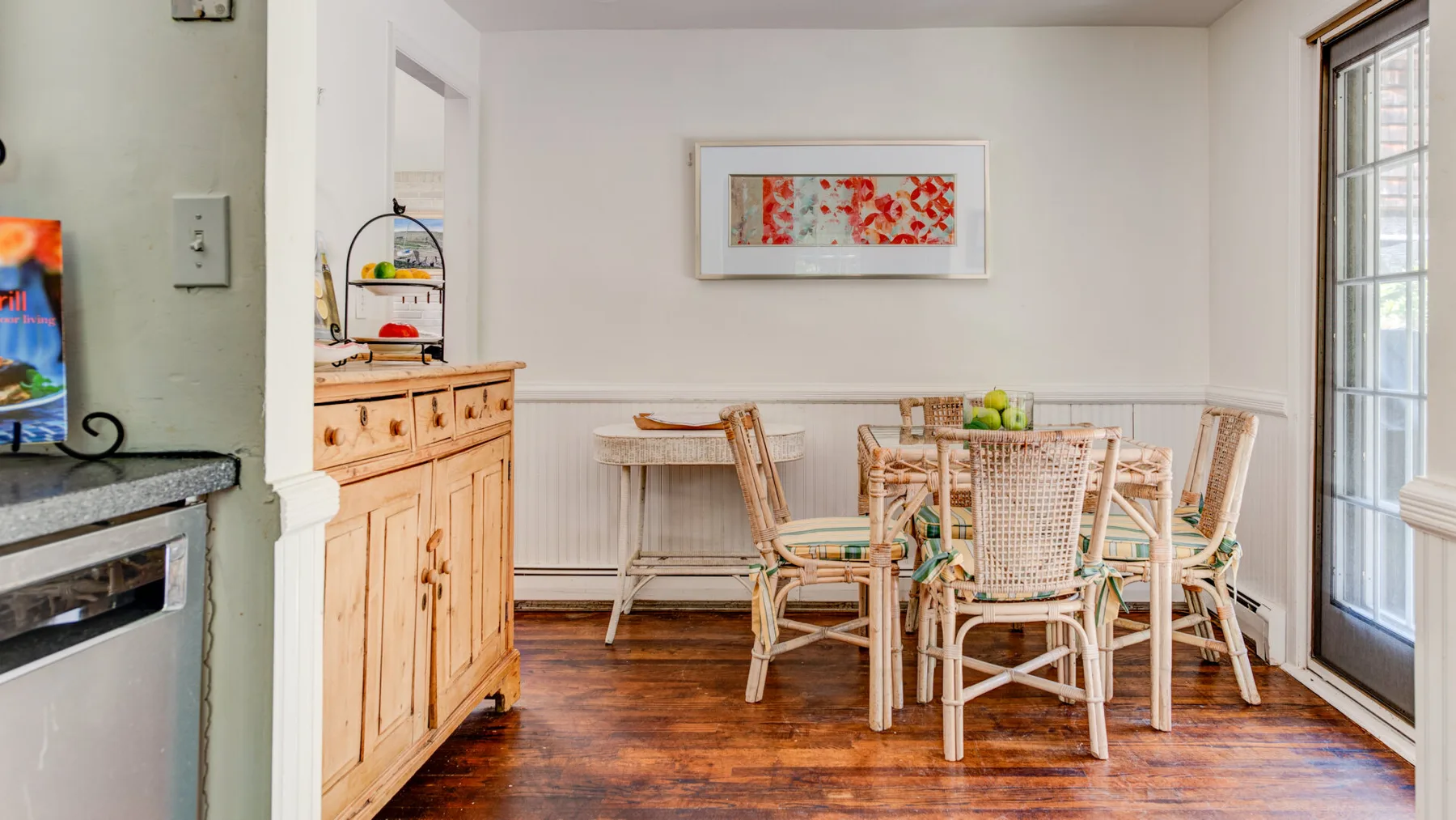 A dining area with a wooden table and woven seating beside a glass door.