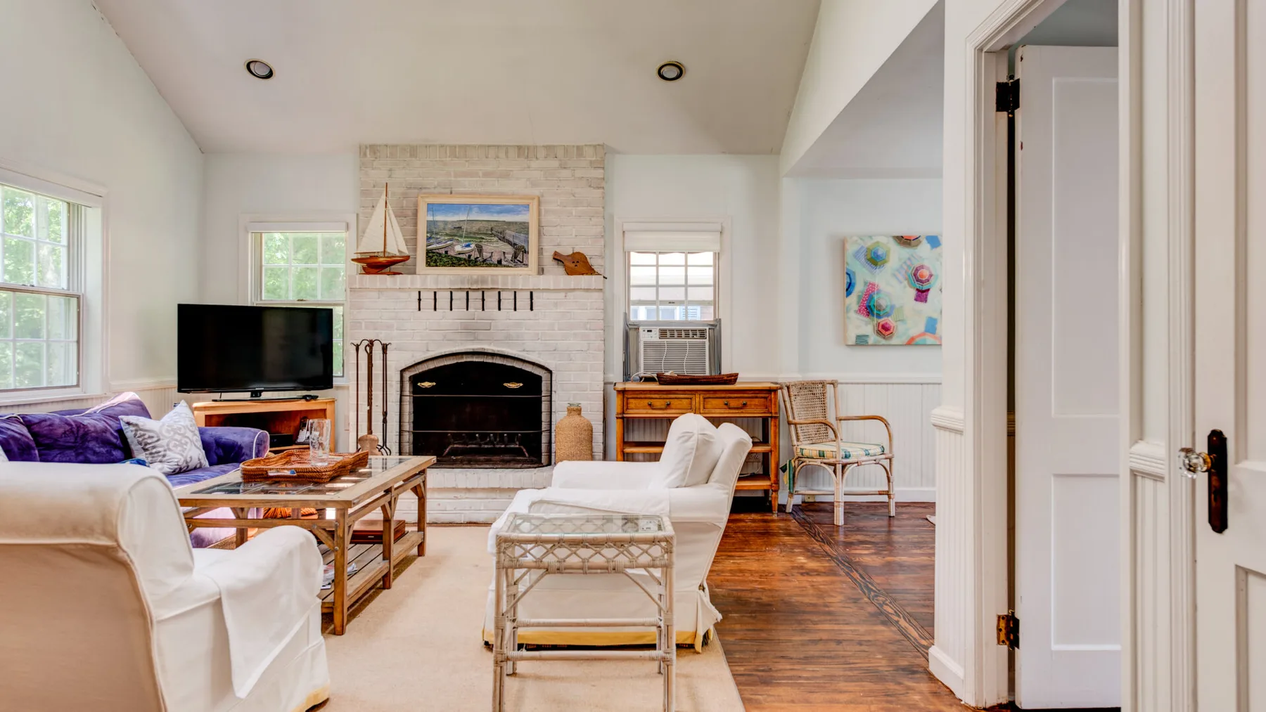 A bright living room with seating, a fireplace, and a television.