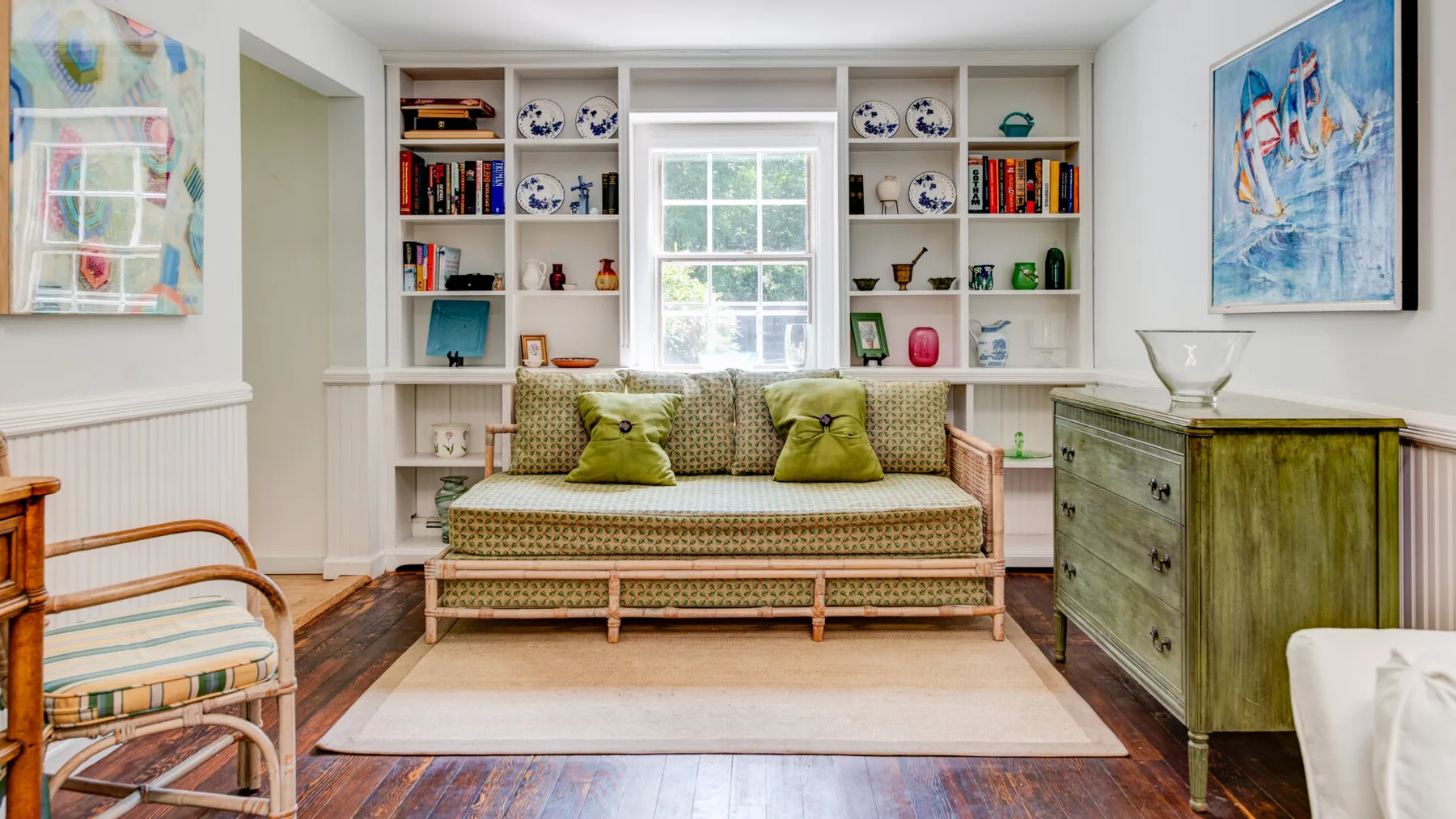 A bright sitting room with built-in bookshelves and a cushioned daybed.