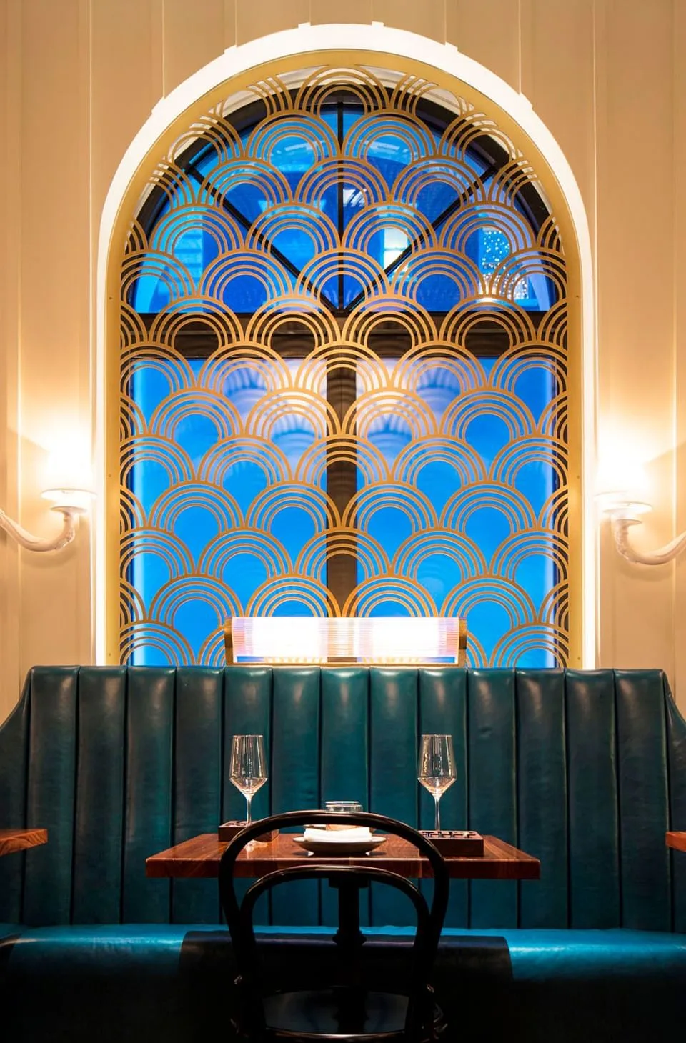 Ciaorigato Restaurant interior with a gold-patterned arch window, teal booths, and dining tables