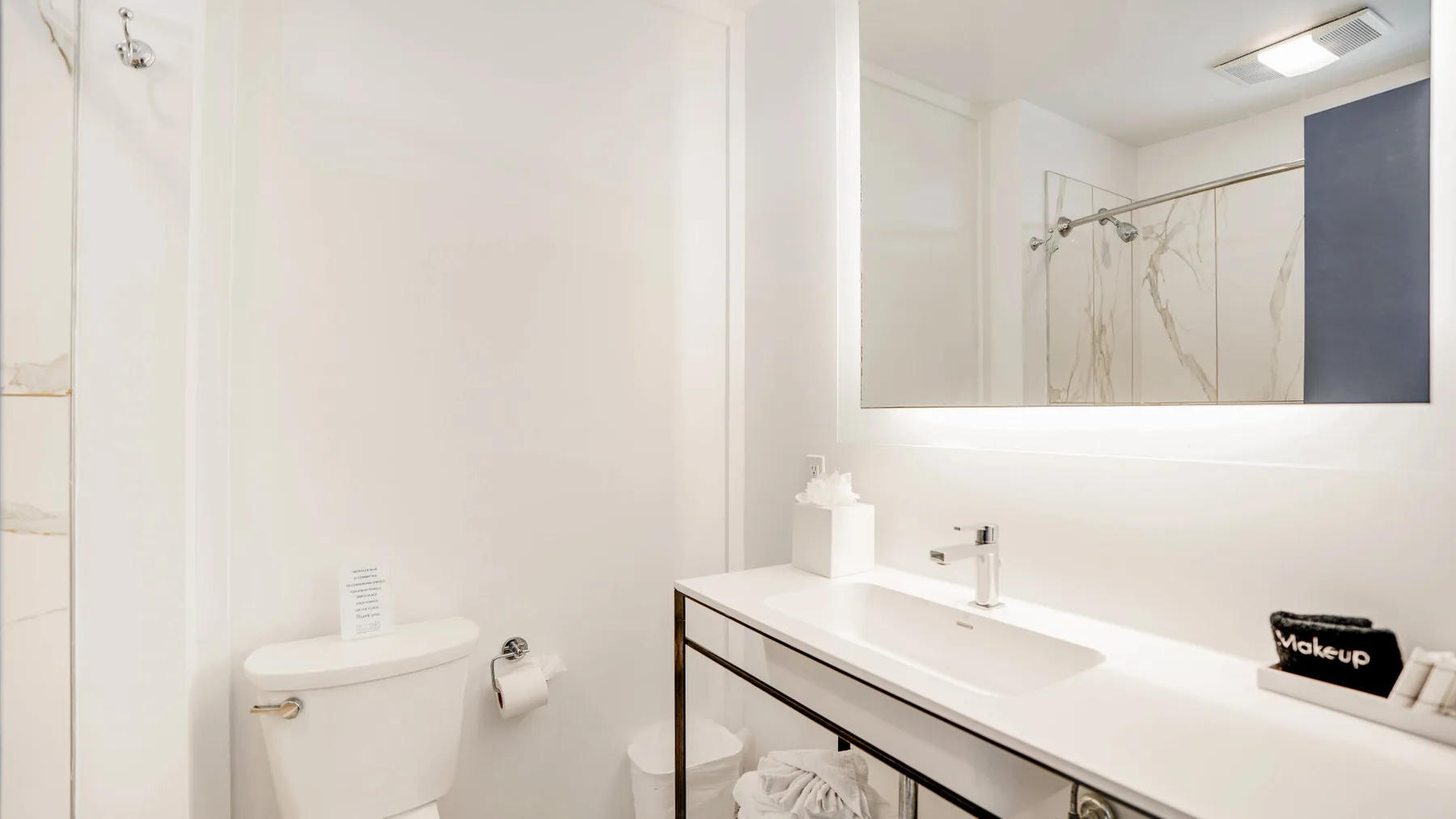 Un baño luminoso con una encimera de lavabo larga y un espejo grande en la pared.