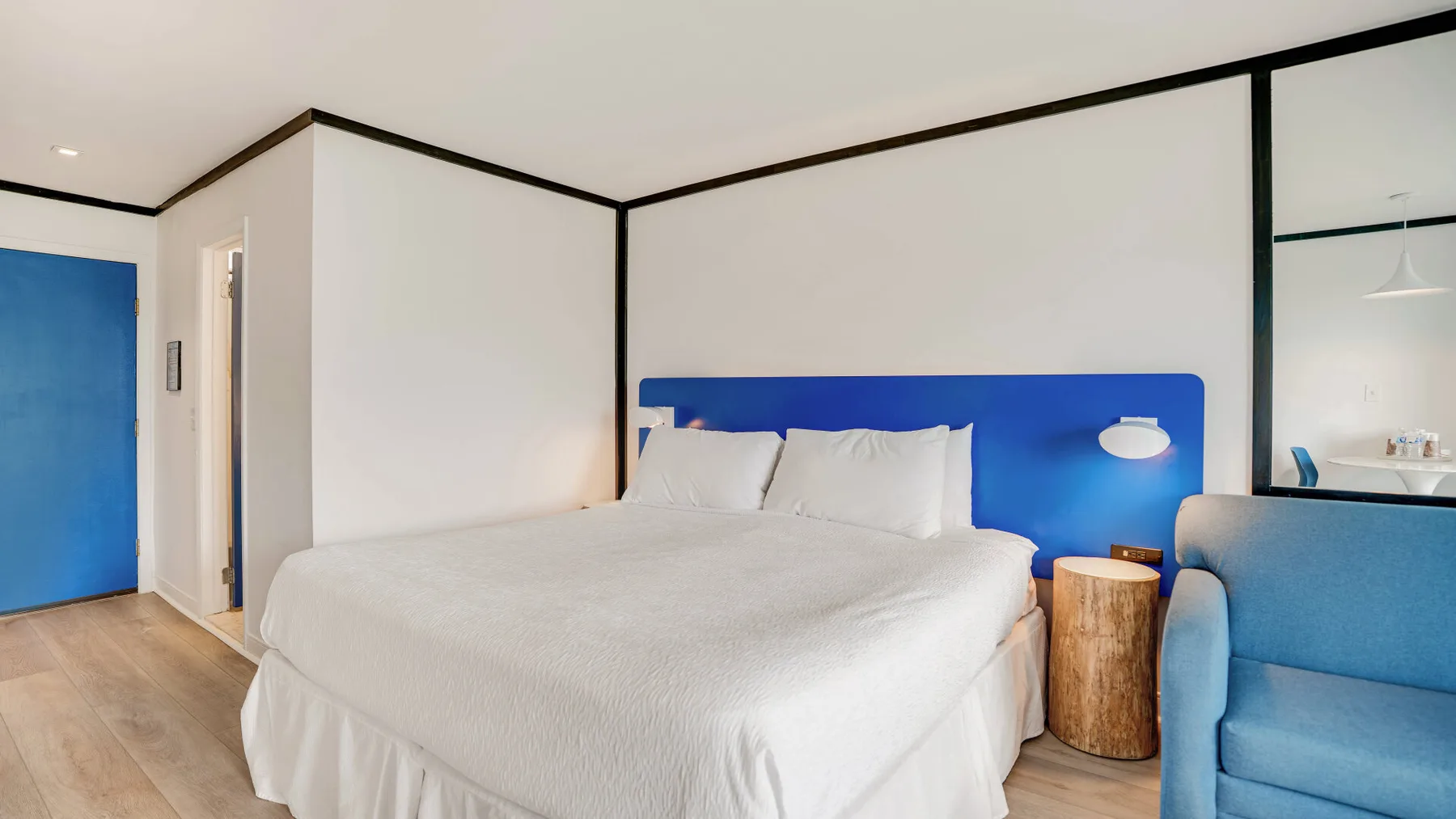 Un dormitorio con una cama grande, un cabecero azul y asientos azules.