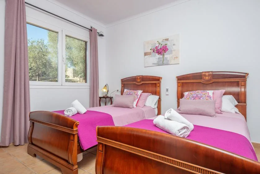 A bedroom with two wooden beds, pink bedding, and a window.