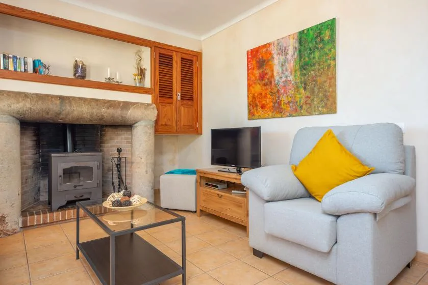 A living room with a fireplace, television, and light-colored seating.