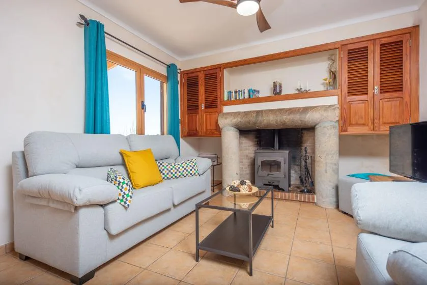 A living room with light-colored seating, a coffee table, and a fireplace.