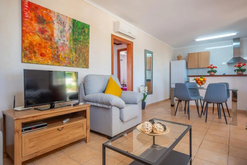 A living and dining area with seating, a television, and a table.