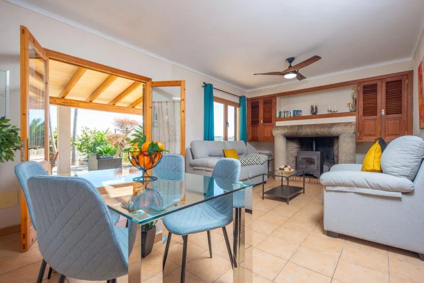 A living room with seating, a glass dining table, and a fireplace.