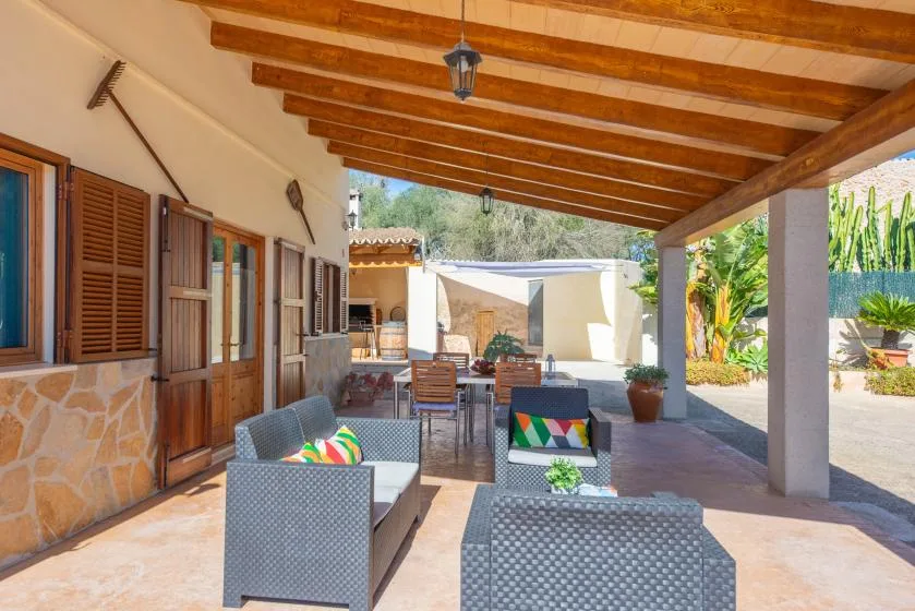 A covered outdoor seating area with wooden beams and garden views.