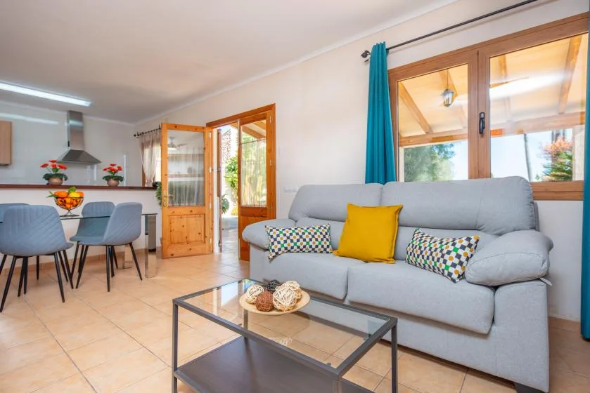 A bright living and dining area with a gray sofa and a glass coffee table.