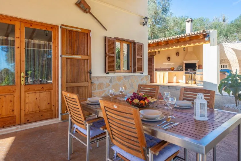 An outdoor dining area with a wooden table set beside the house.