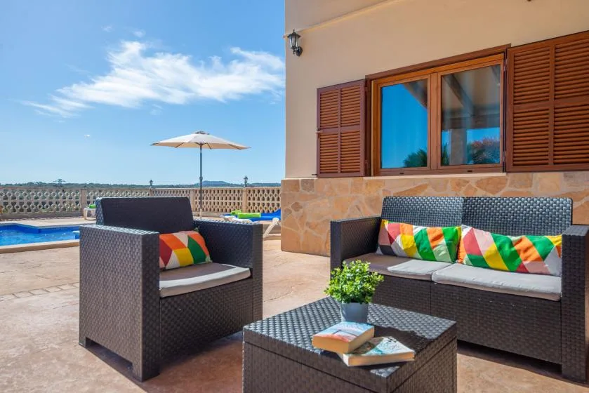 A patio seating area beside a pool, with colorful cushions and a small table.