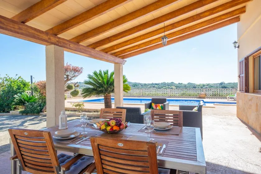 A shaded outdoor dining area overlooks a swimming pool and landscaped grounds.