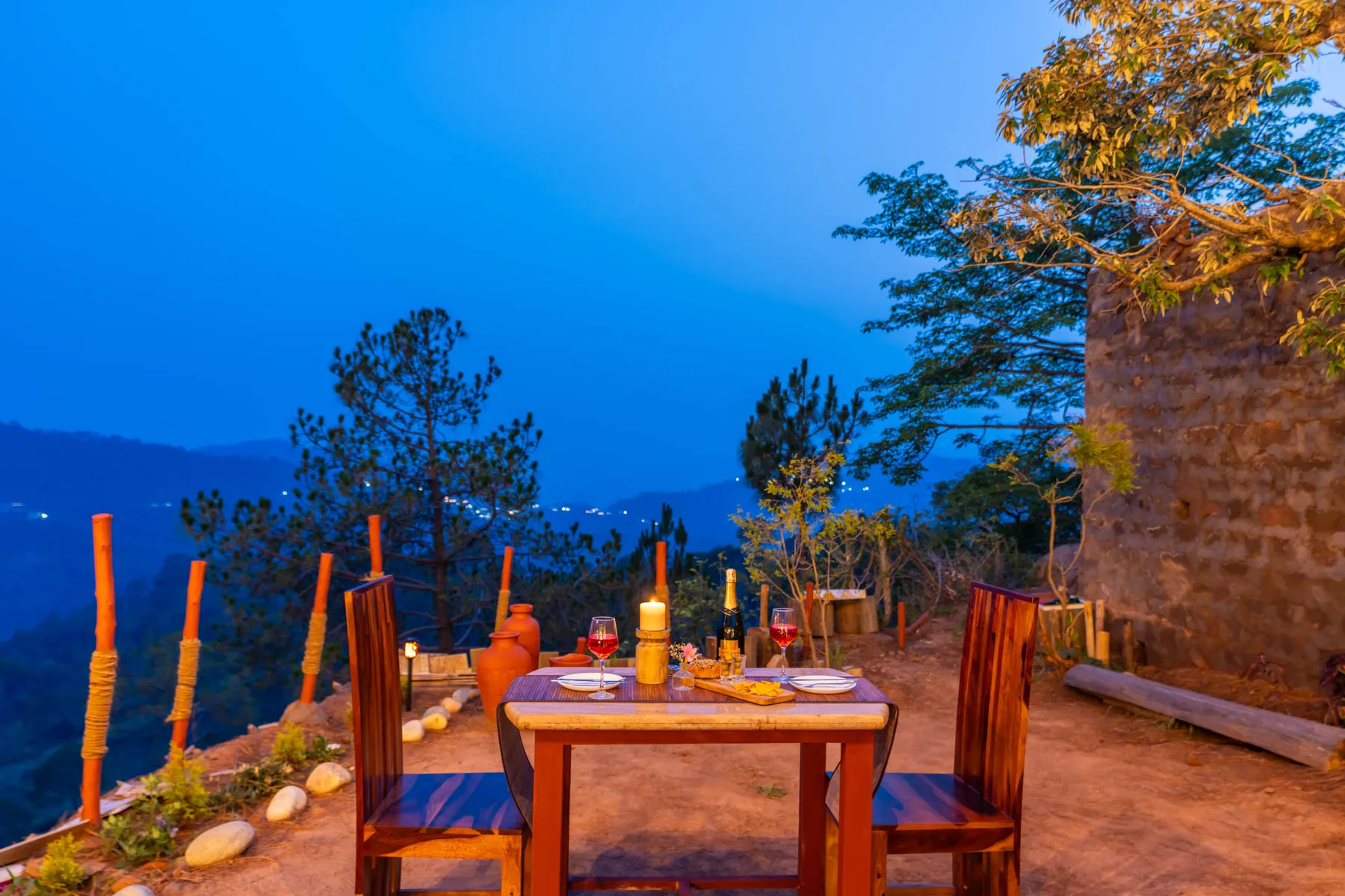 An outdoor dining area with a wooden table and chairs overlooking a mountain landscape.