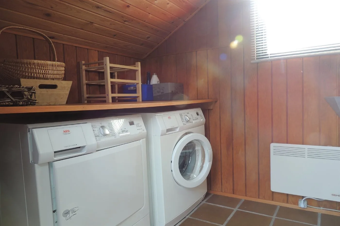 Cuarto de lavado con lavadora y secadora bajo una encimera de madera.