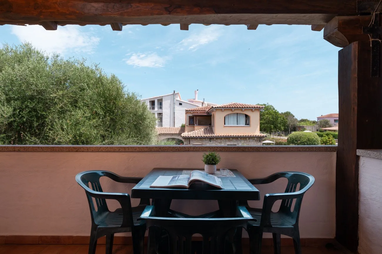 Una terraza cubierta con mesa y asientos da a casas cercanas.