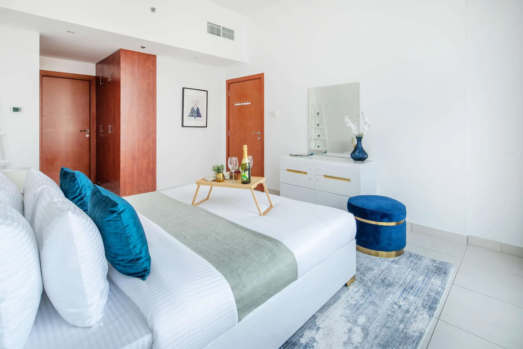 A bright bedroom with a bed, a small table, and a dresser.