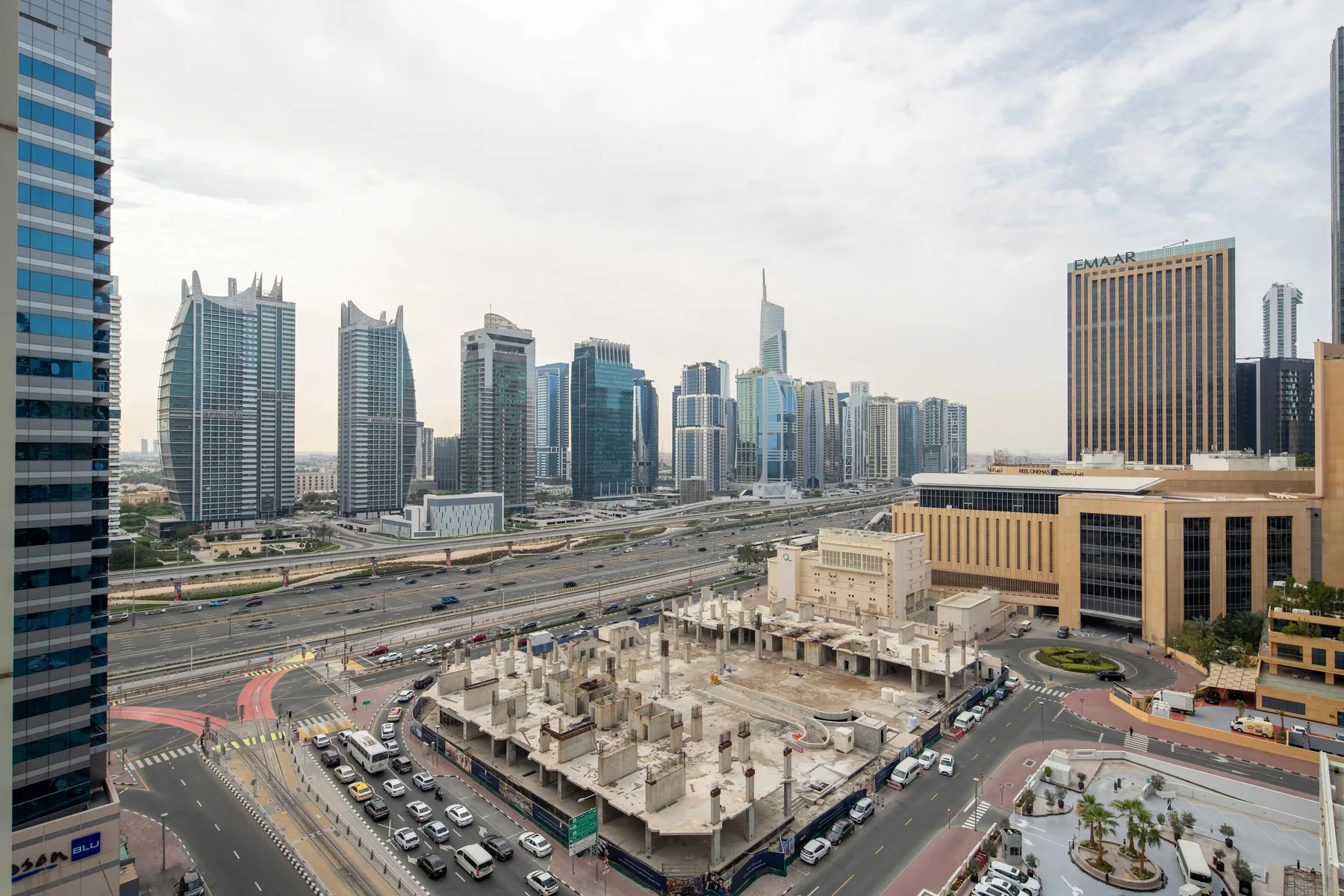A city skyline rises beyond multilane roads and a construction site.
