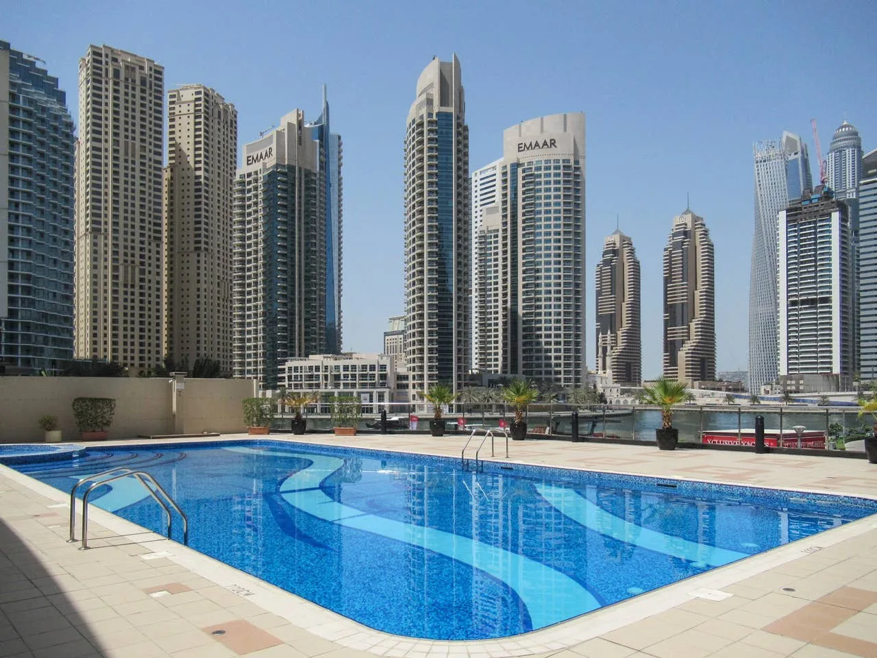 An outdoor swimming pool sits in front of a skyline of tall buildings.