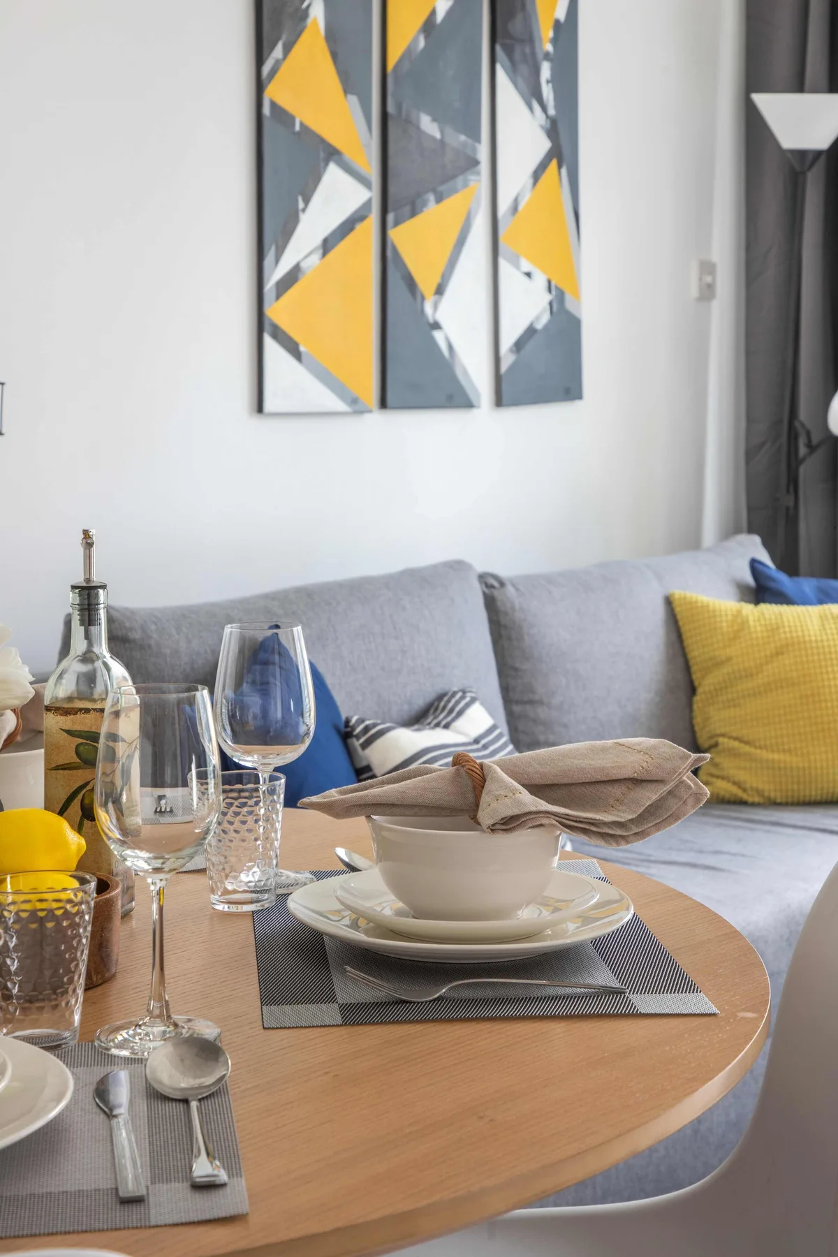 A living room with a set dining table in front of a gray sofa.