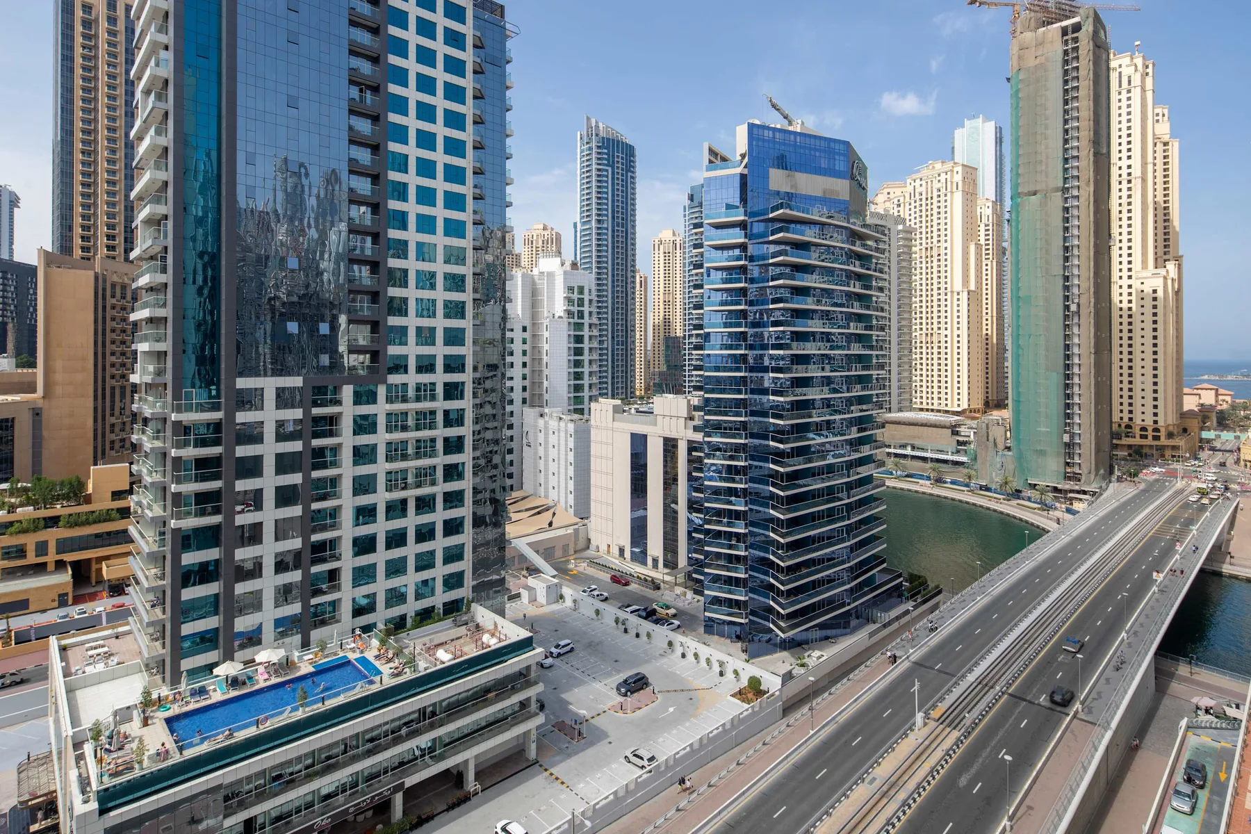 A city skyline of high-rise buildings beside an elevated road and waterway.