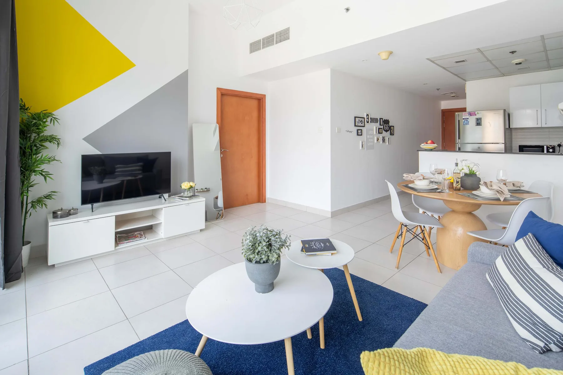 Una luminosa sala de estar y comedor de planta abierta con televisor y mesa de comedor.