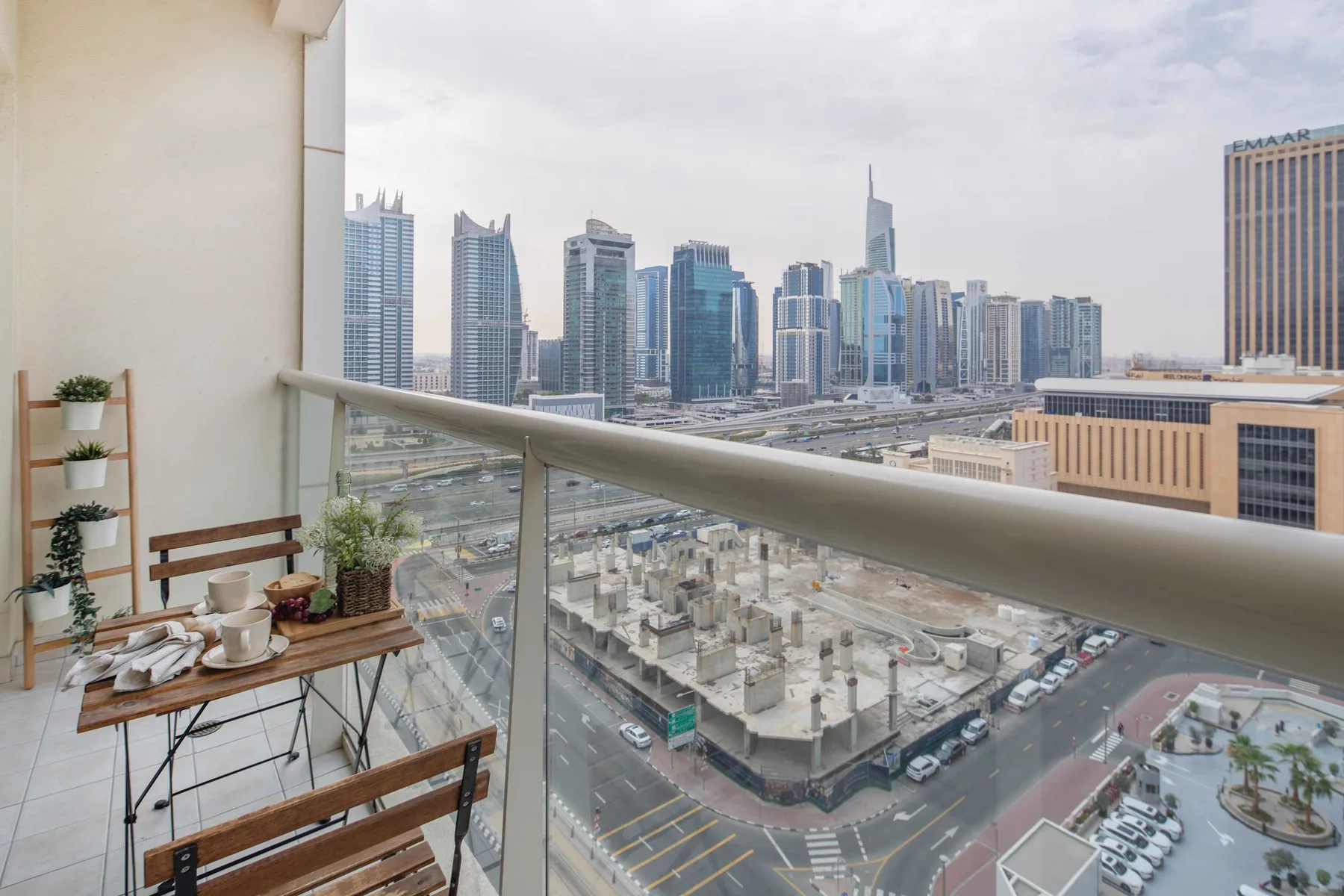 A balcony overlooks a city skyline, with a glass railing in the foreground.