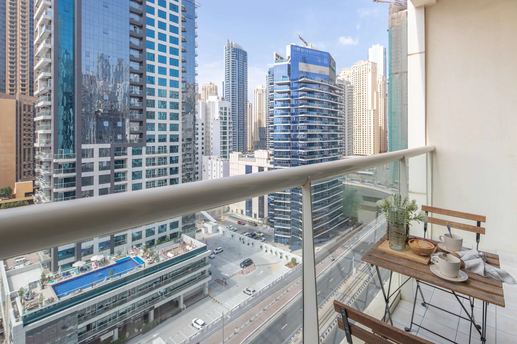 A balcony overlooks a cluster of modern high-rise buildings, with a small table and chairs.
