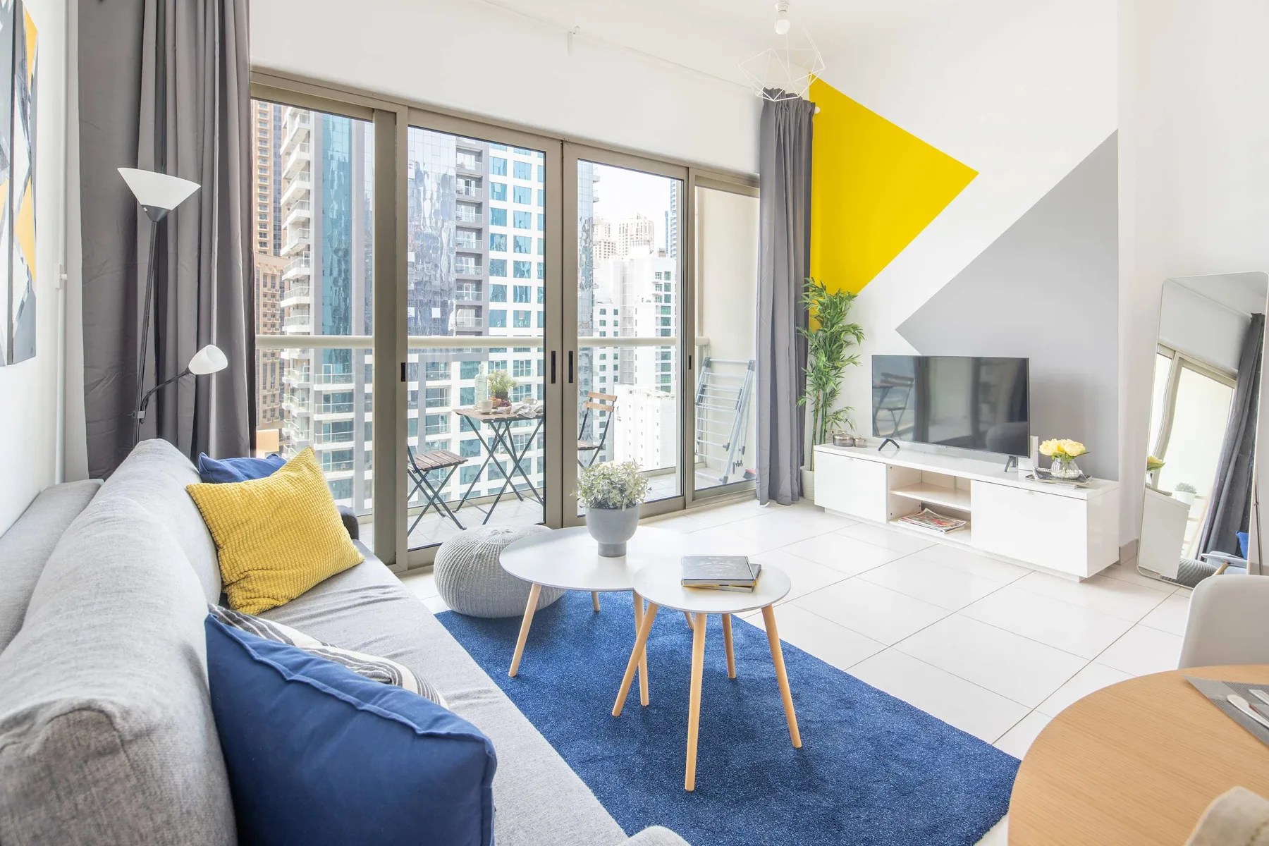 Una sala de estar luminosa con una ventana grande, asientos y un televisor.