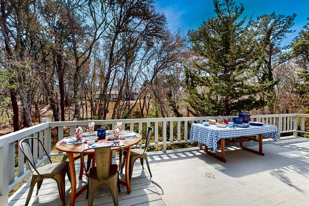 An outdoor deck with tables set for dining, surrounded by trees.