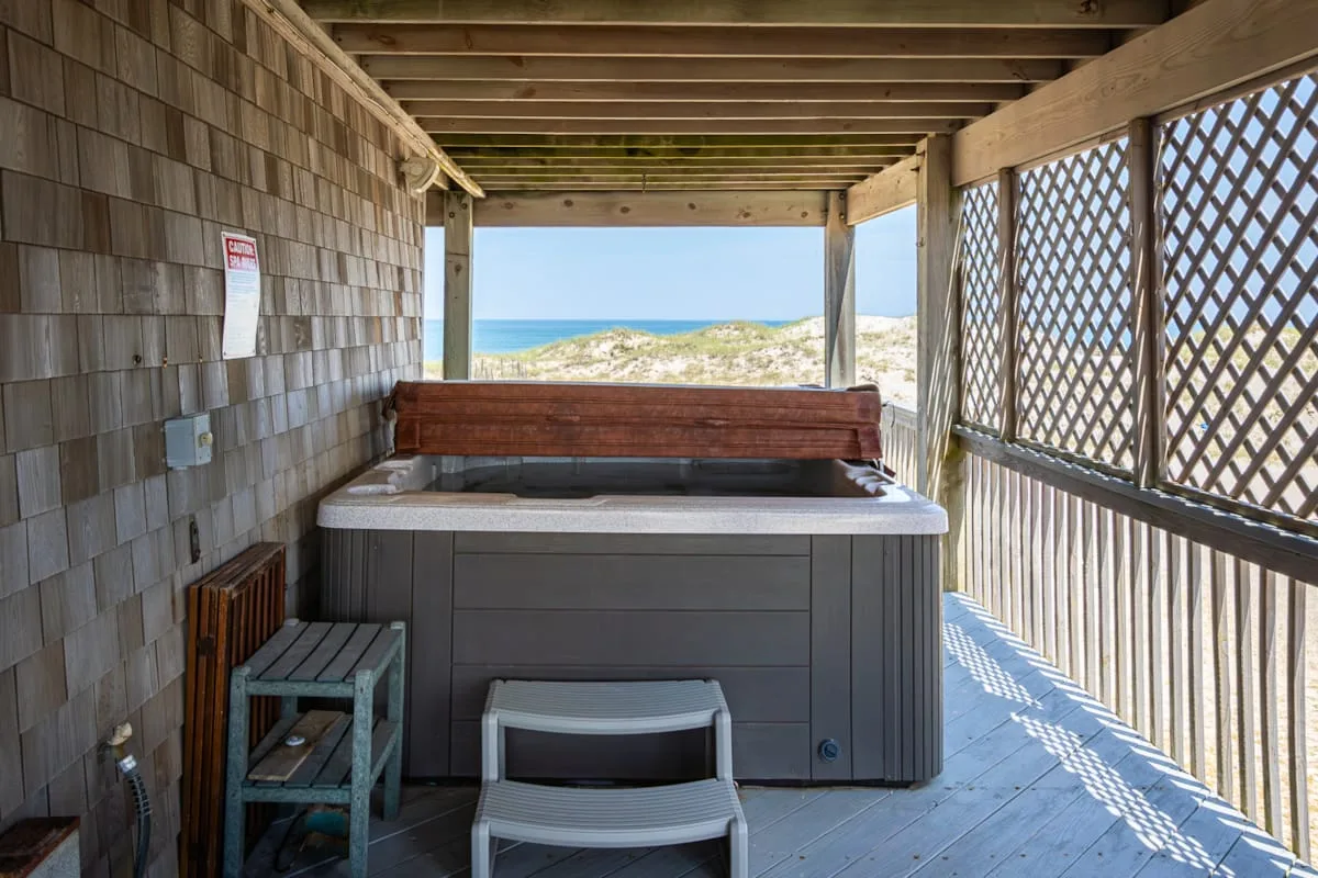 Una zona cubierta de bañera de hidromasaje da a una playa de arena y al océano.