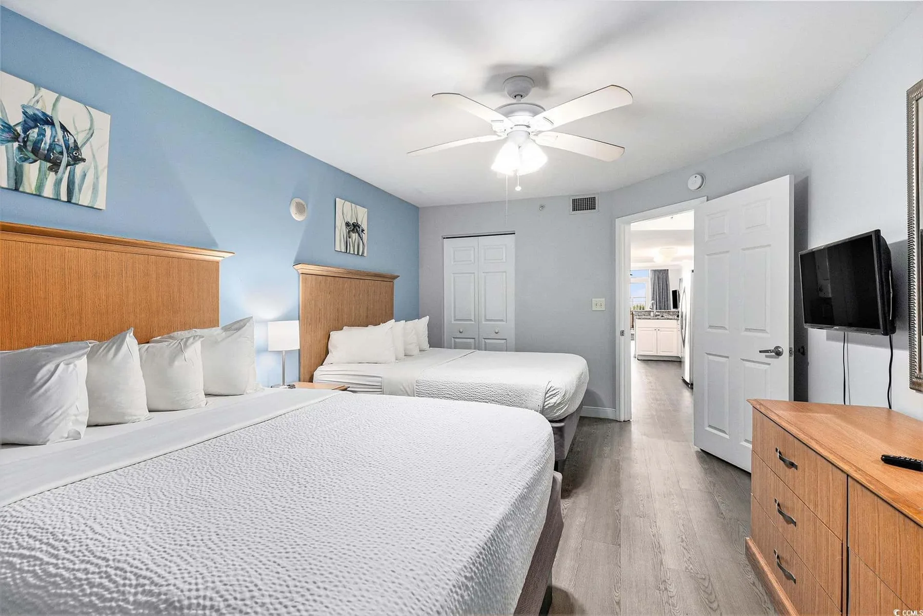 A bedroom with two beds, blue walls, and a ceiling fan.