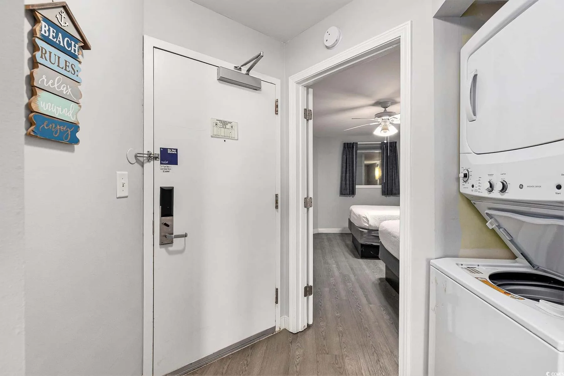 A room entry opens onto a bedroom with beds and a ceiling fan.