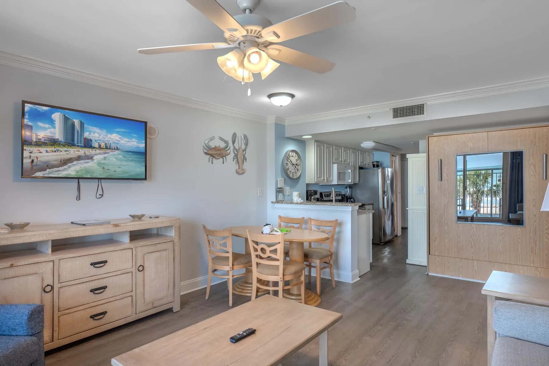 A dining and living area opens onto a kitchen, with a ceiling fan overhead.