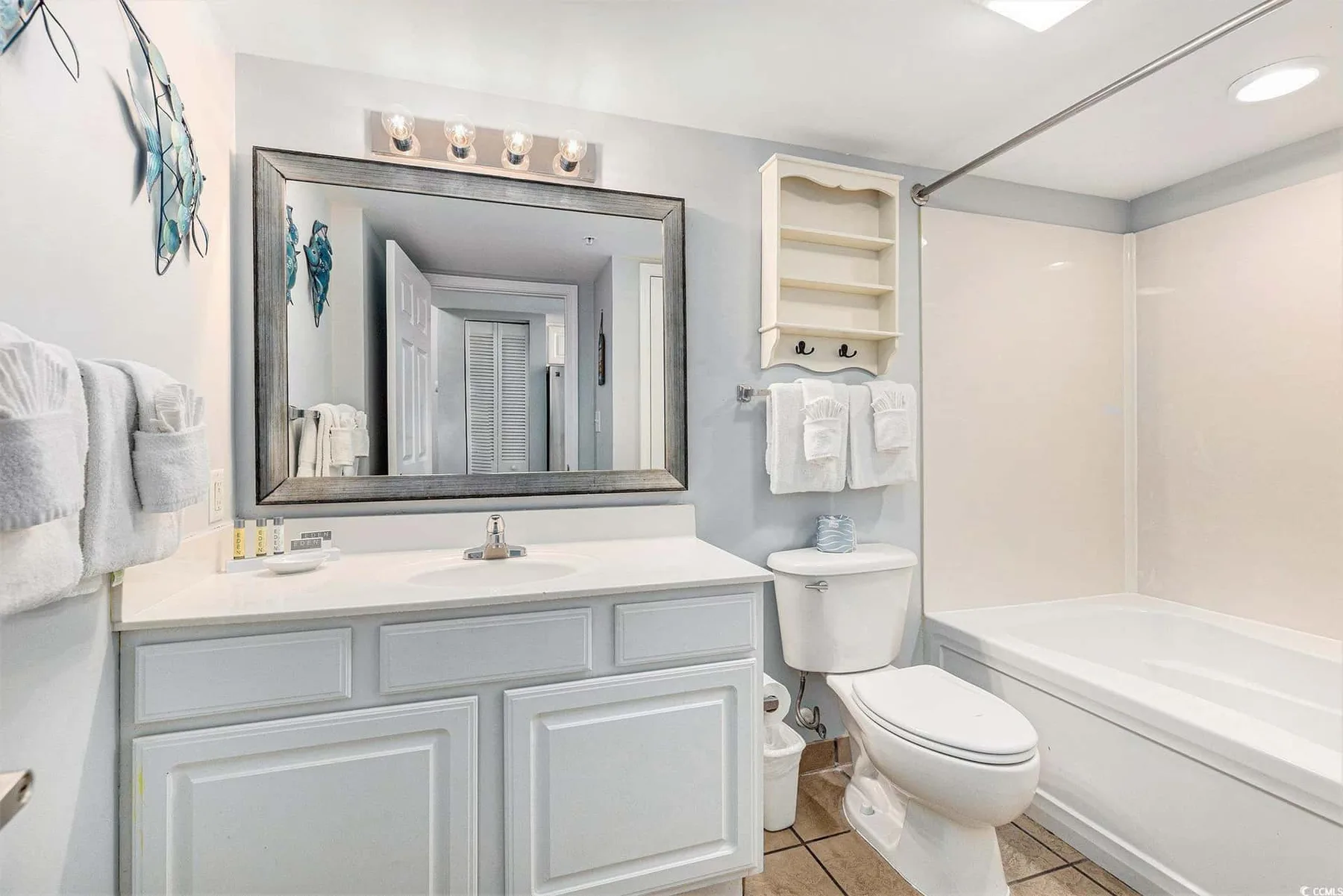 A bathroom with a vanity, mirror, toilet, and bathtub.