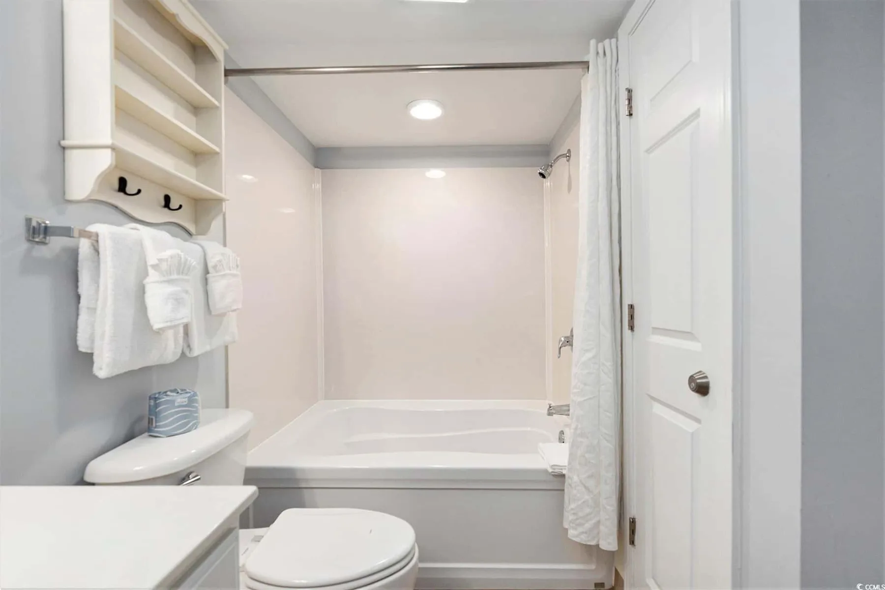 A bright bathroom with a bathtub, shower curtain, and white towels.