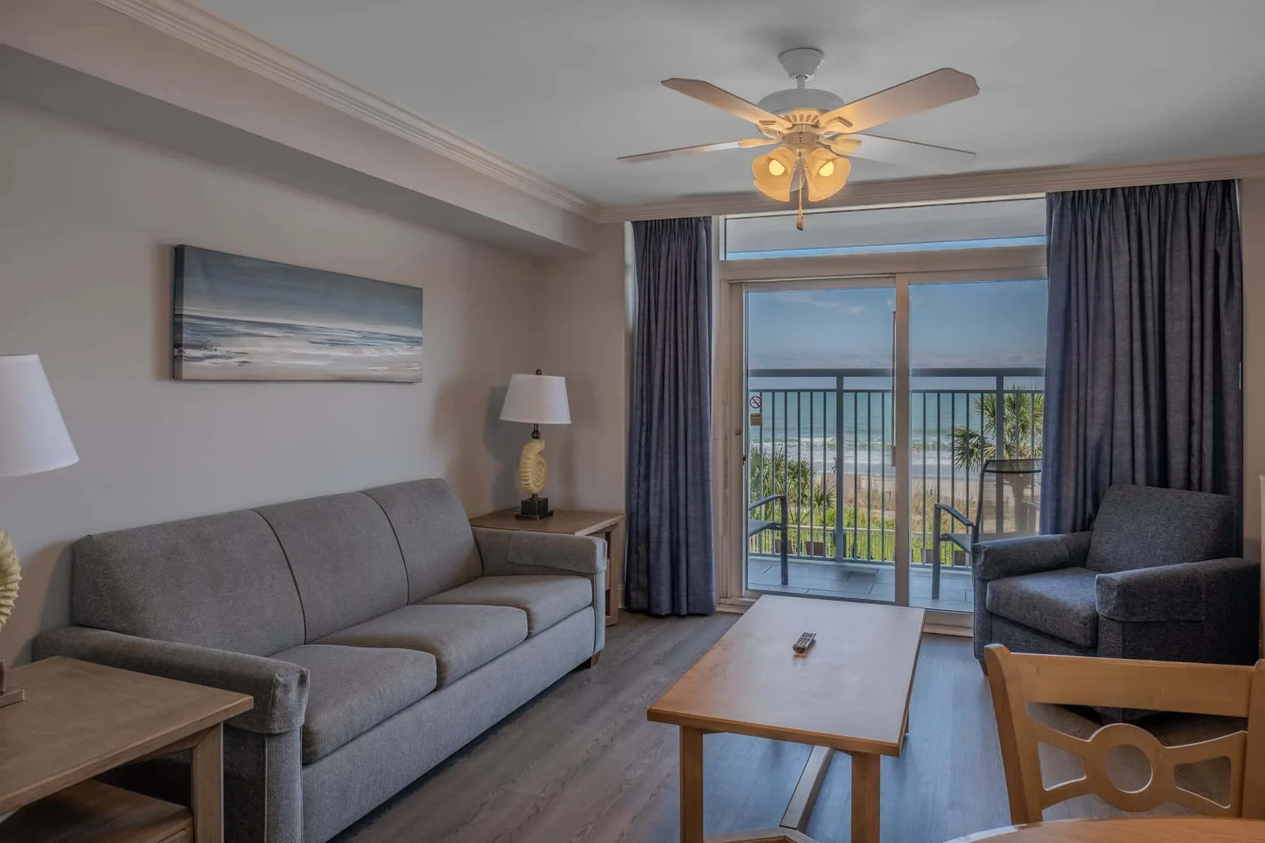 A living room with seating, a coffee table, and glass doors opening to a balcony.