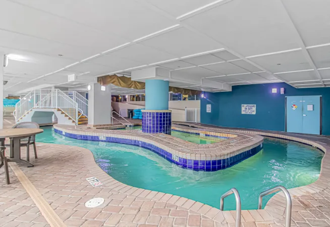 An indoor swimming pool with a curved edge and tiled deck.