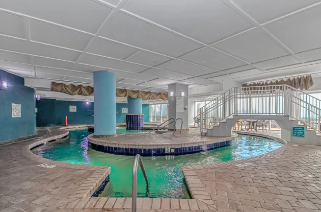 An indoor swimming pool with turquoise water and a raised central platform.