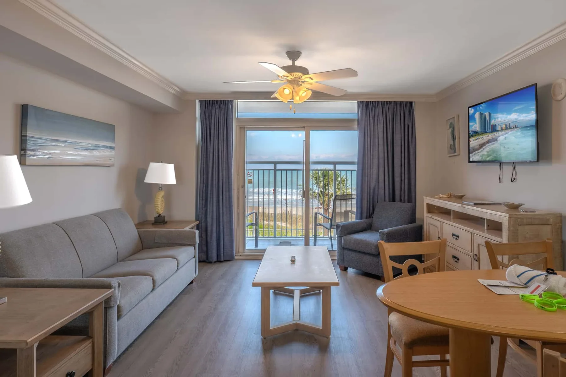 A living room with seating, a coffee table, and glass doors opening to a balcony.