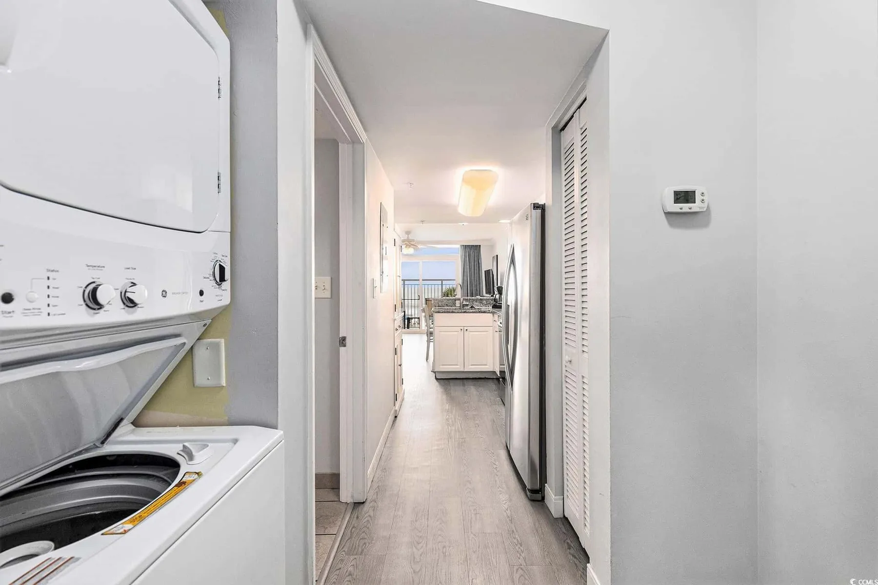 A laundry area opens onto a hallway leading to a bright kitchen.