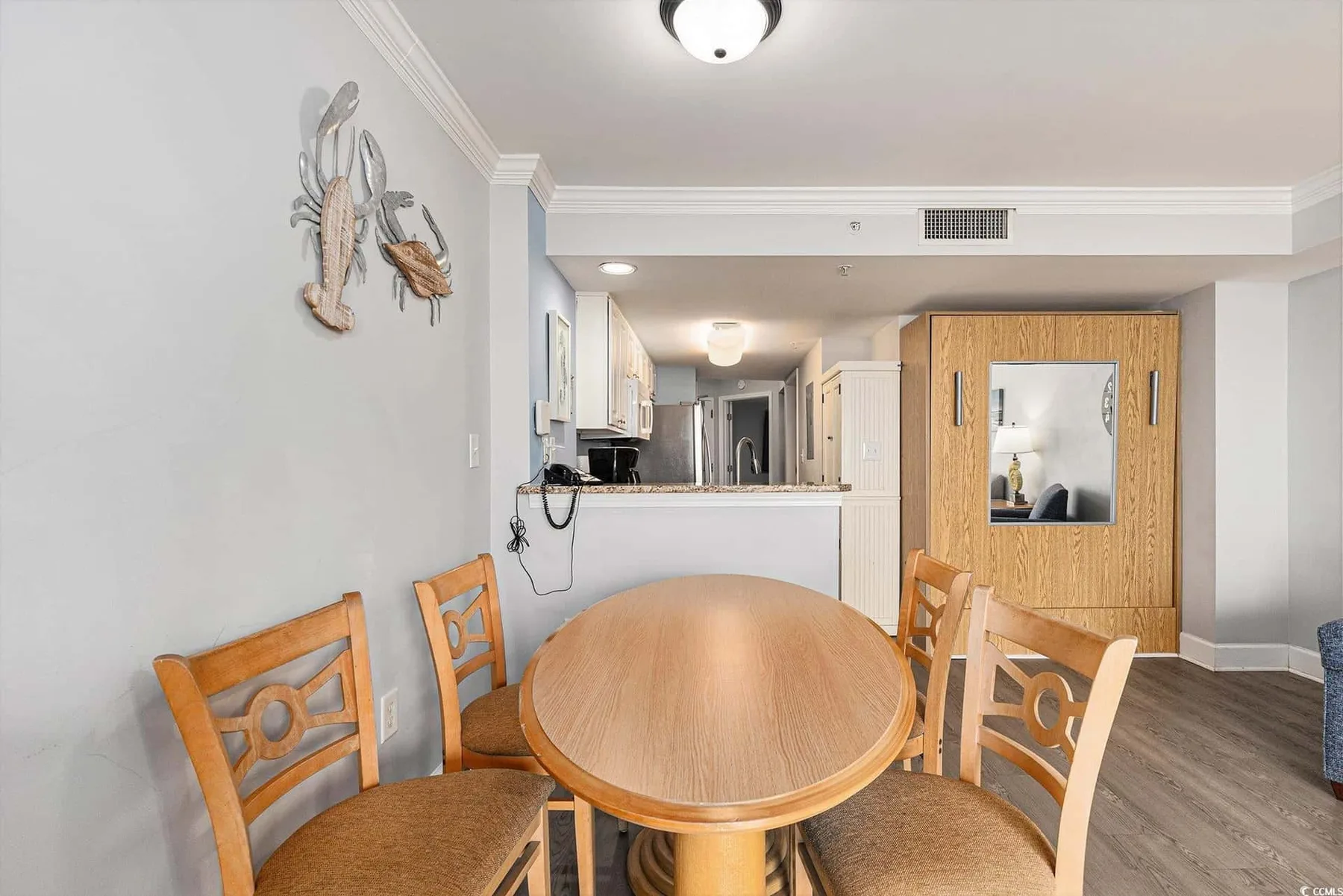 A dining area with a round wooden table and chairs beside an open kitchen.
