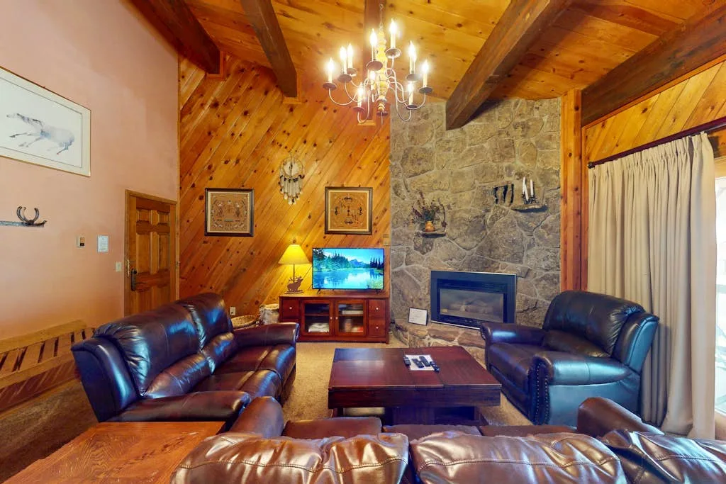 A wood-paneled living room with leather seating and a stone fireplace.